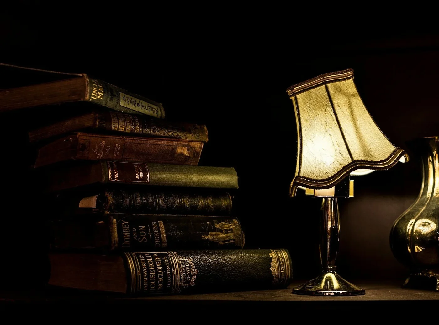 Stack of old books beside a lamp